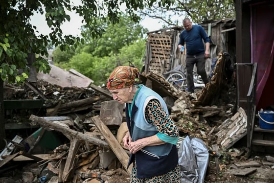 Женщина возле разрушенного ракетным обстрелом дома в городе Бахмуте / Meduza