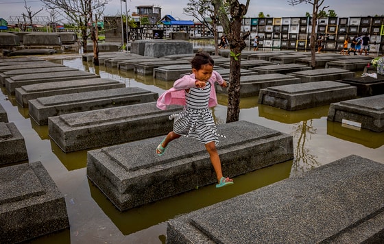Filippindagi Nalgae tropik bo‘ronidan keyin qiz suv bosgan qabristondagi qabrlardan sakrab ketmoqda&nbsp; Foto: Ezra Acayan/Getty&nbsp;