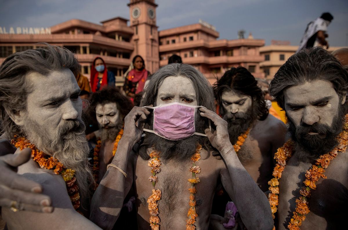 Нага Садху, или индуистский святой человек, одевает маску перед процессией для купания в реке Ганг во время Фестиваля кувшинов в Харидвар, Индия, 12 апреля 2021 г. REUTERS / Danish Siddiqui<br>