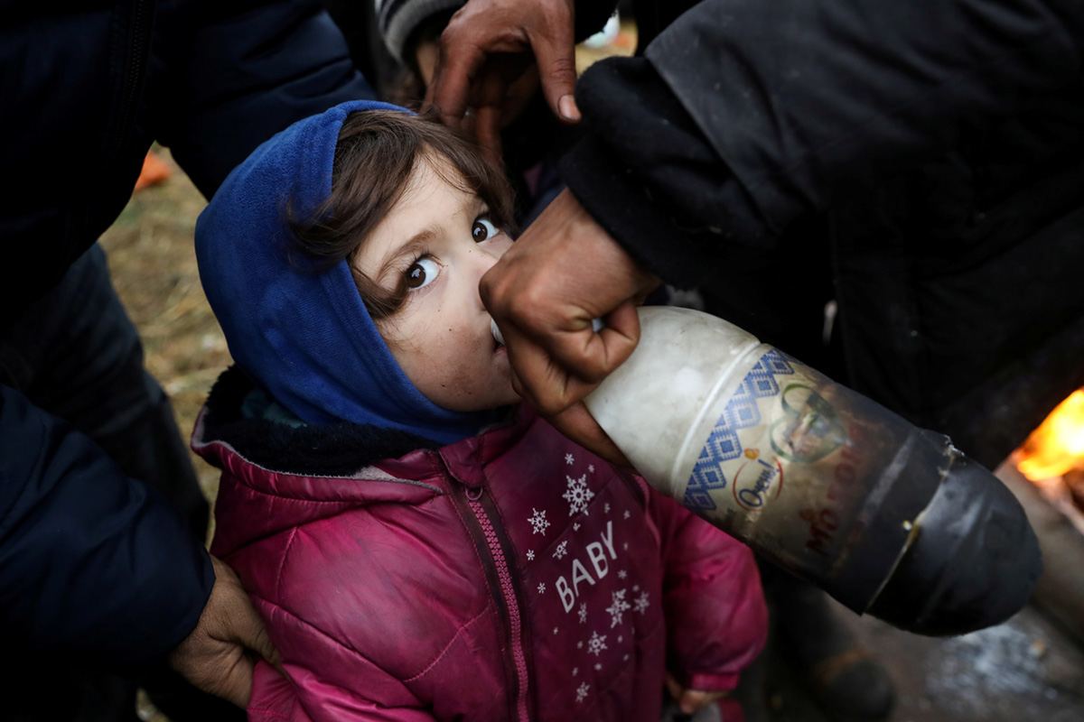 Ребенок пьет молоко в временном лагере мигрантов в ТЛЦ «Брузги» на белорусско-польской границе в Гродненской области, Беларусь, 18 ноября 2021 г. REUTERS / Kacper Pempel