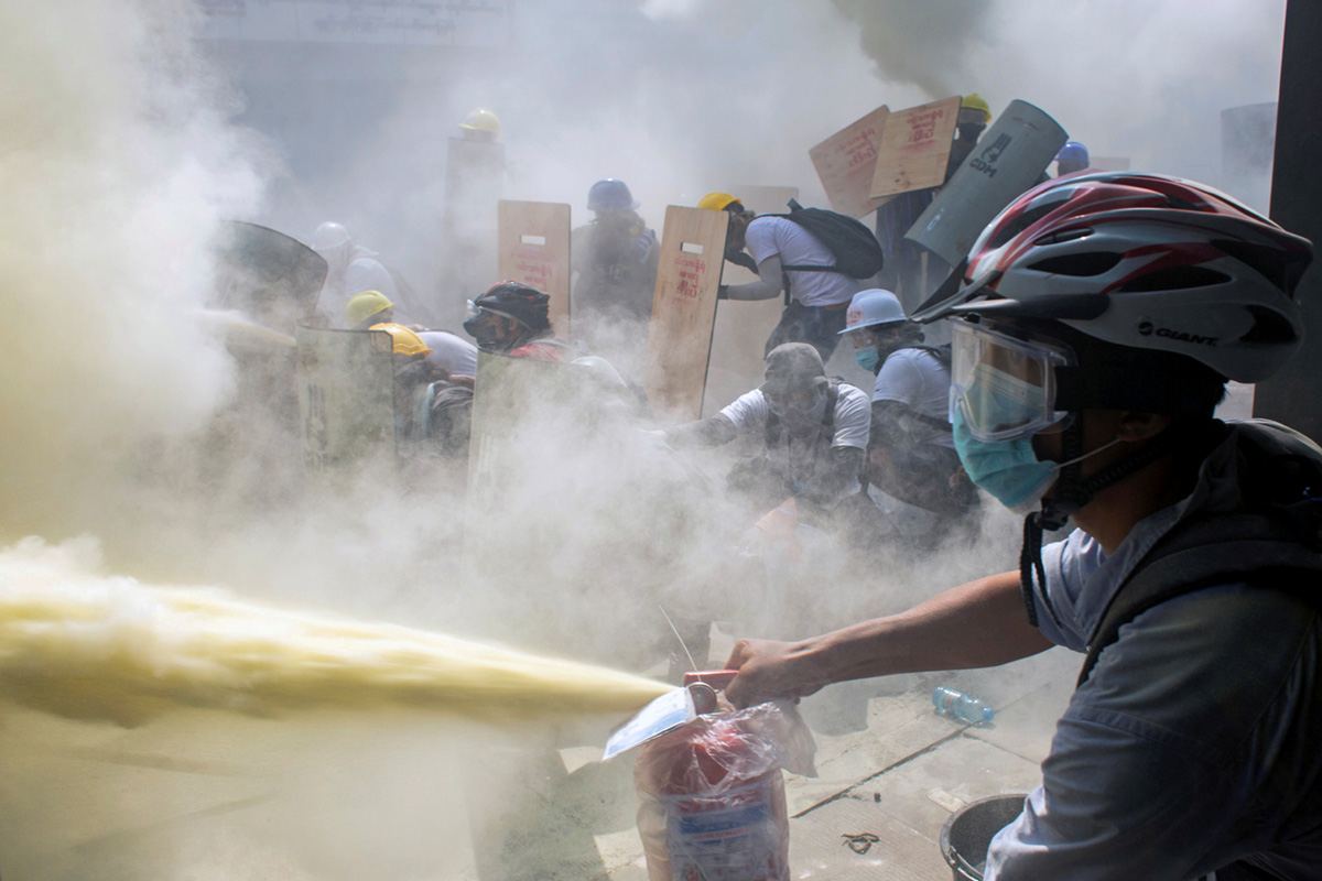 Протестующий использует огнетушитель во время столкновения демонстрантов с полицейскими во время акции протеста против военного переворота в Янгоне, Мьянма. 28 февраля 2021 г. REUTERS / Stringer<br>