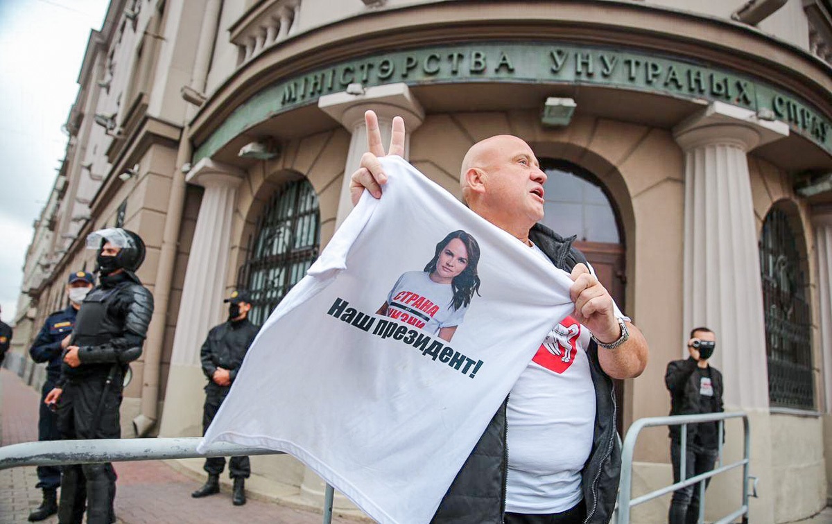 Мужчина держит белую футболку с изображением альтернативного кандидата Светланы Тихановской у входа в Министерство внутренних дел.