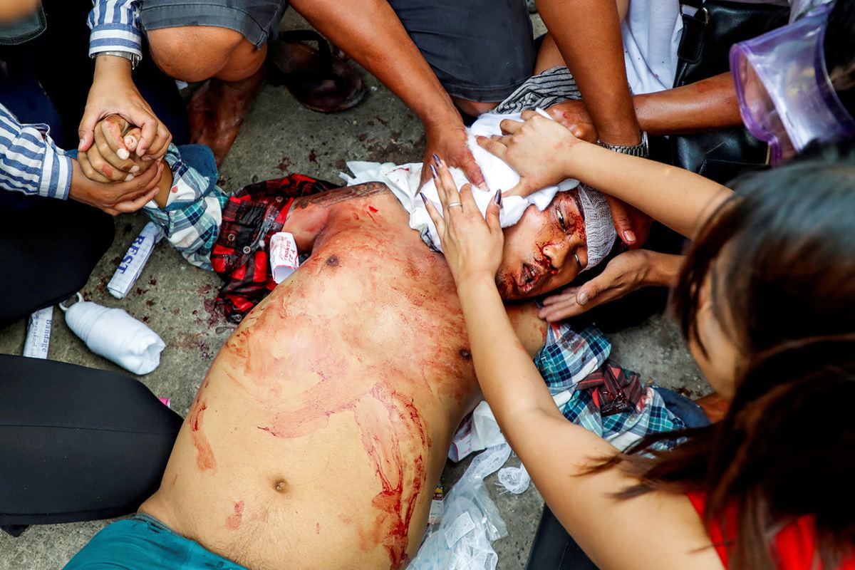 Протестующие пытаются оказать первую помощь активисту после того, как он был убит выстрелом в голову во время разгона протеста против переворота в Янгоне, Мьянма.17 марта 2021 г. REUTERS / Stringer